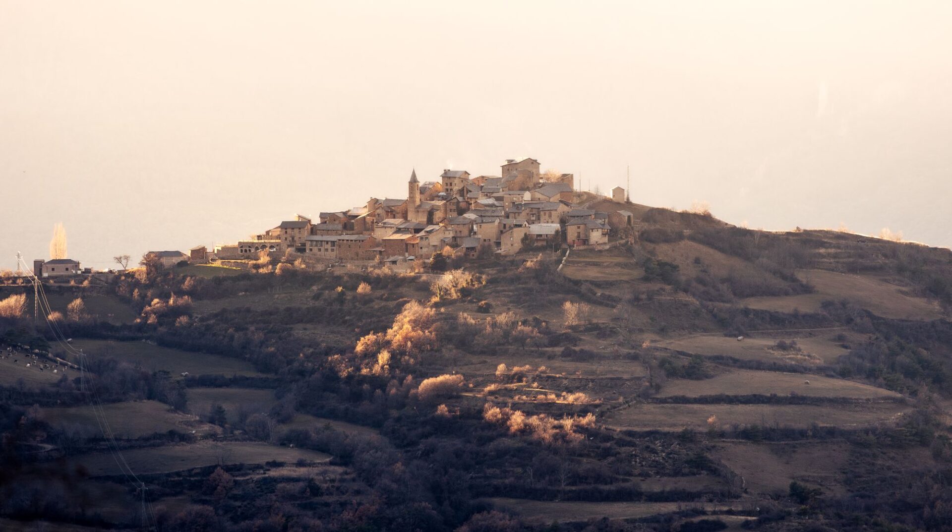 Hügellandschaft mit einem Dorf auf der Anhöhe im Abendlicht